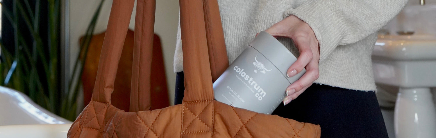 Woman holding a brown quilted handbag and a white bottle in a room with plants and a sink.
